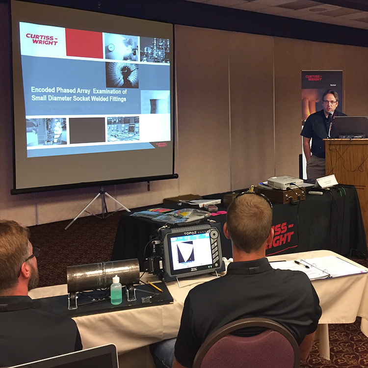 Curtiss-Wright employee stands at a podium during a PAUT training workshop